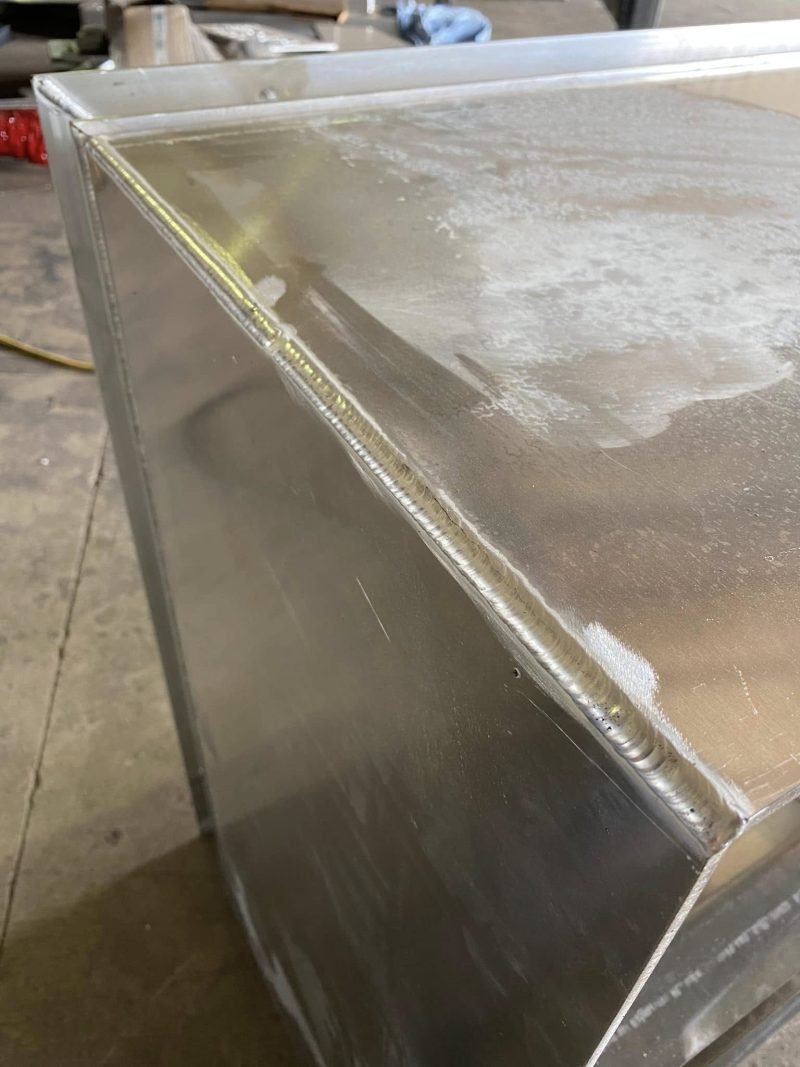 Ground and welded corner of an aluminum enclosure