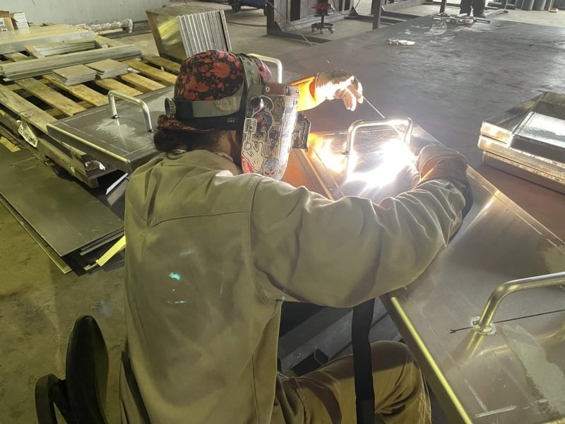 Welder laying a bead on a steel plate in the H&L Fabrication shop in Lafayette