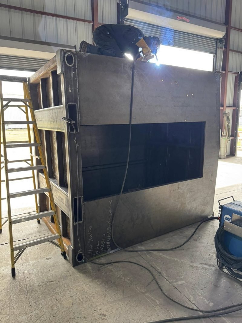 Welding the top of a steel enclosure from a ladder